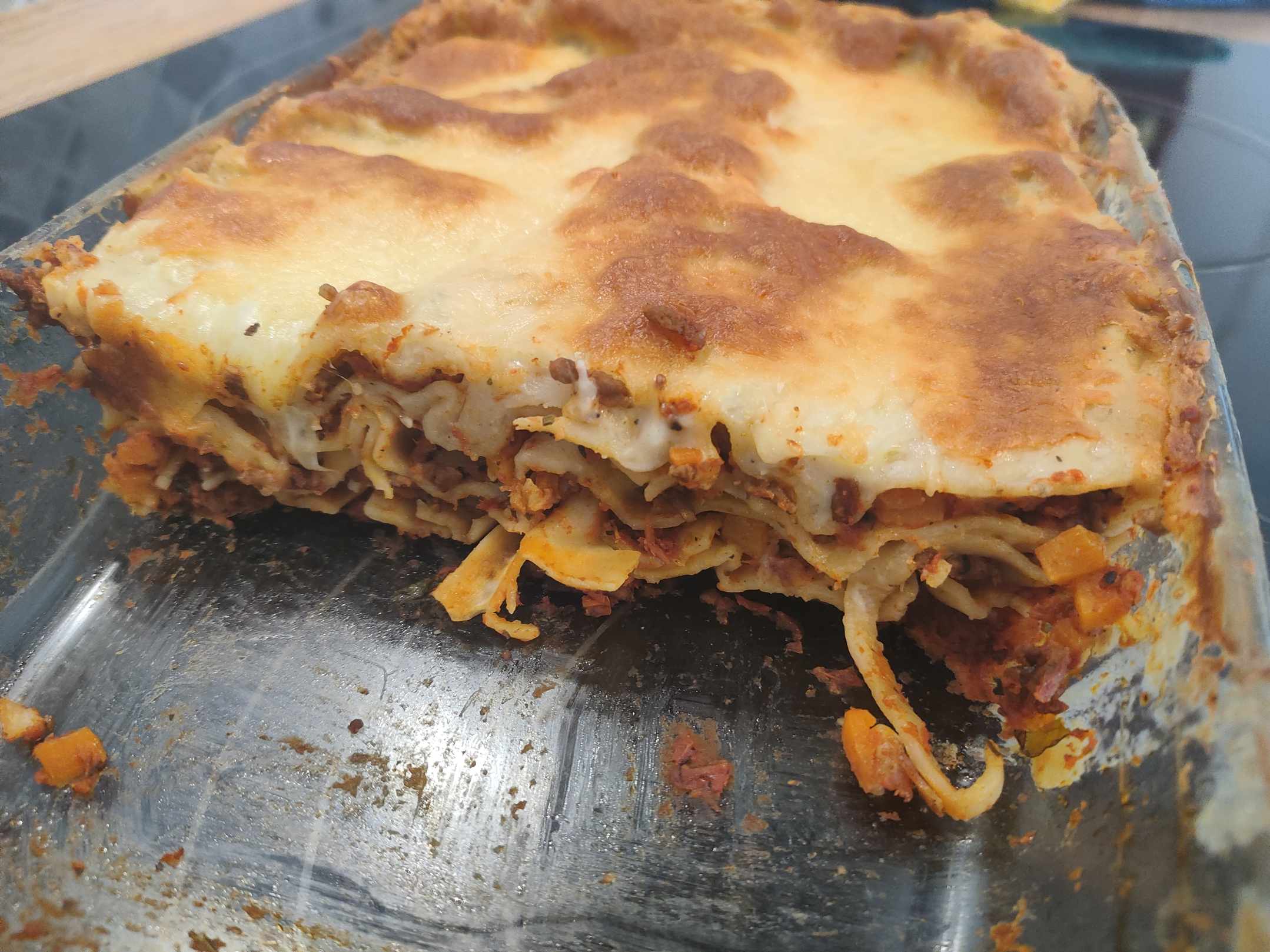 Aufgeschnitte Lasagne auf einem Teller. Man kann die leckeren Schichten der Lasagne sehen.