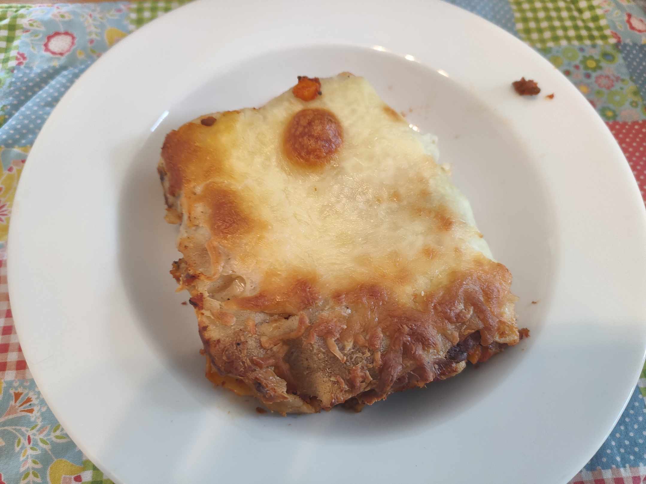 Eine Portion Lasagne auf einem Teller. Die lecke Käsekruste ist bestens zu sehen.
